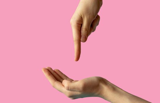 Close-up of women's hands, side view with the palm up, and the second hand points a finger at the palm. isolated on pink background.