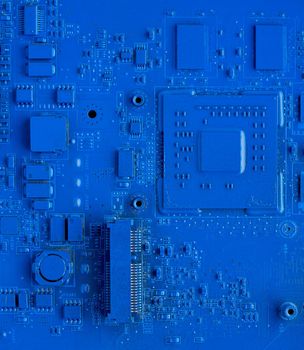 Computer motherboard. Classic blue background with pc backdrop, close up. Single color microchip, top view, vertical