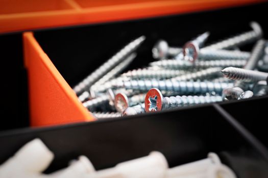 Close up of a pile of stainless-steel screws in a toolbox. Metal screw, iron screw, chrome screw. Industrial and construction concept.