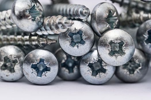 Close up of a pile of multipurpose metal screws. Multipurpose screw heads. Industrial and construction concept. Metal screw, iron screw, chrome screw.