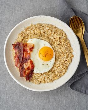 Oatmeal, fried egg and fried bacon. Hearty fat high-calorie breakfast, source of energy. Balance of proteins, fats, carbohydrates. Balanced food, clean eating. Intuitive conscious food. Lactose free