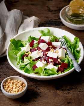Healthy salad with beet, curd, feta and pine nuts, lettuce. Low carb keto ketogenic dash diet. Dark food photography. Vertical