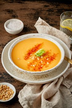 Autumn pumpkin soup with smoked paprika, pine nuts, vegetarian dish, healthy and dieting food on dark background, top view, vertical