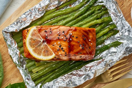Foil pack dinner with fish. Fillet of salmon with asparagus. Healthy diet food, keto diet, Mediterranean cuisine. Oven-baked hot dinner. Top view, macro