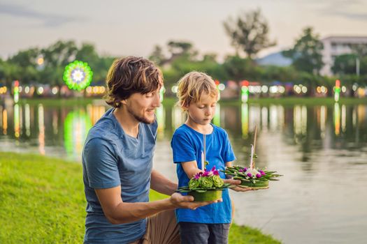 Father and son tourists celebrates Loy Krathong, Runs on the water. Loy Krathong festival, People buy flowers and candle to light and float on water to celebrate the Loy Krathong festival in Thailand.