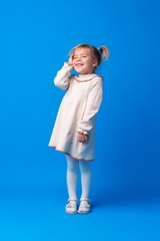 Full length portrait of a little girl standing on blue backgorund, close up