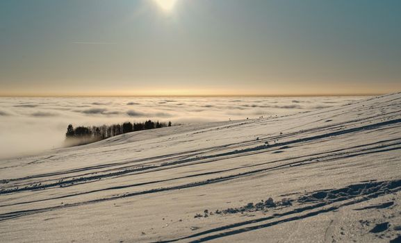 The concept of relaxing in the mountains in winter in the snow on skis, snowboards or sleds, walking under the setting sun at sunset on the Wasserkuppe mountain in Hesse Germany. High quality photo