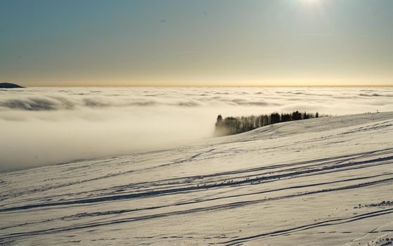 The concept of relaxing in the mountains in winter in the snow on skis, snowboards or sleds, walking under the setting sun at sunset on the Wasserkuppe mountain in Hesse Germany. High quality photo