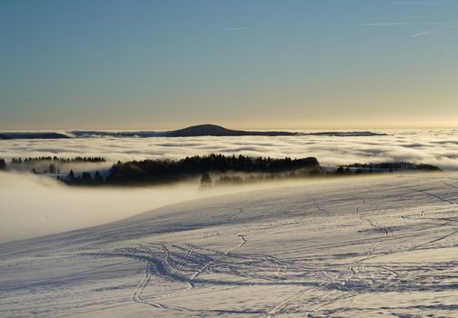 The concept of relaxing in the mountains in winter in the snow on skis, snowboards or sleds, walking under the setting sun at sunset on the Wasserkuppe mountain in Hesse Germany. High quality photo