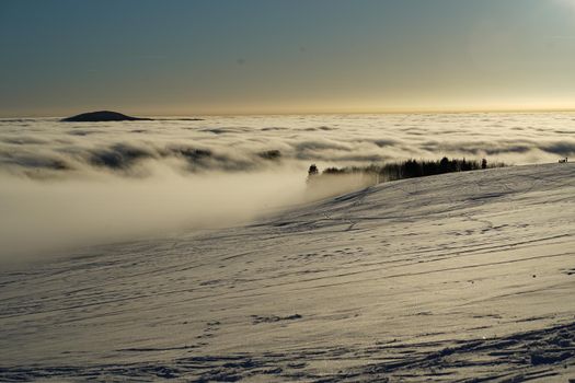 The concept of relaxing in the mountains in winter in the snow on skis, snowboards or sleds, walking under the setting sun at sunset on the Wasserkuppe mountain in Hesse Germany. High quality photo