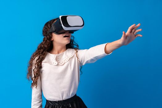 Girl with virtual reality glasses on blue background, close up