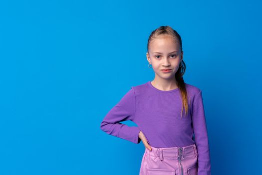 Portrait of a little smiling girl preteen on blue background, close up