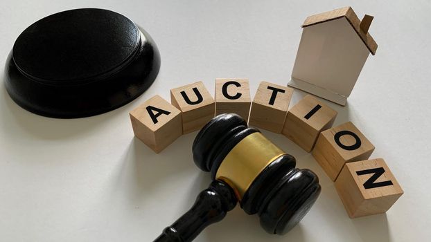 Auction text on wooden blocks with mini house and gavel background.