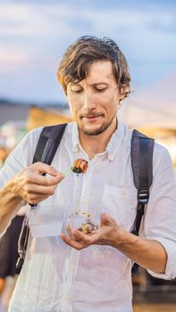 Young man tourist on Walking street Asian food market. VERTICAL FORMAT for Instagram mobile story or stories size. Mobile wallpaper