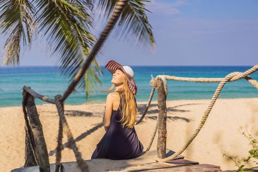 Vacation on tropical island. Woman in hat enjoying sea view from wooden bridge.