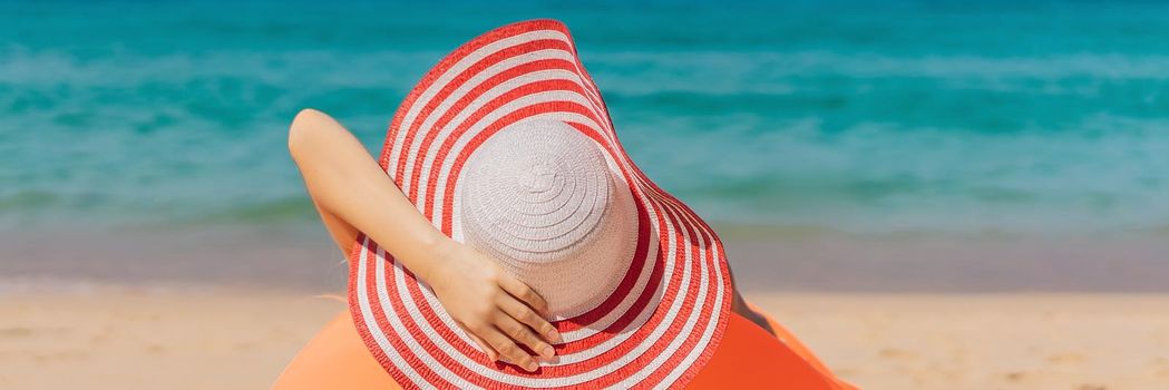 Summer lifestyle portrait of pretty girl sitting on the orange inflatable sofa on the beach of tropical island. Relaxing and enjoying life on air bed. BANNER, LONG FORMAT