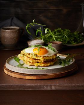 Homemade potato belgian waffles with fried egg, avocado sauce, flying arugula, mozzarella cheese. Levitation. Hearty fat breakfast. Dark brown table. Close up, vertical, copy space