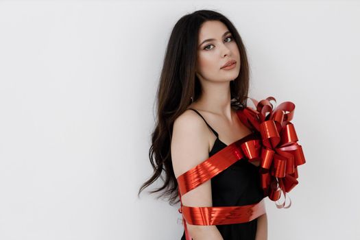 Young pretty woman wrapped with ribbon, red gift ribbon. High quality photo