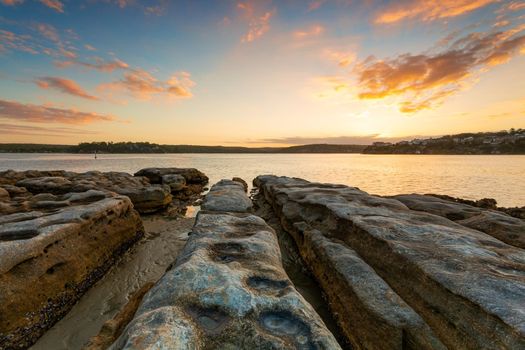 Rocky shoreline of Cronulla in NSW Australia leading towards , the sun setting in the distance