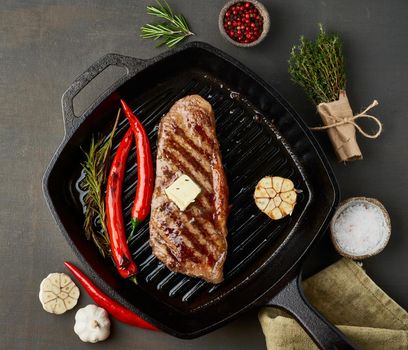 Keto ketogenic diet beef steak, well done fried striploin on grill pan. Paleo food recipe with grilled meat, butter and seasoning. Close up, top view