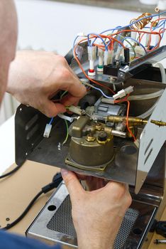 The master repairs the coffee machine. household appliances repair at home concept