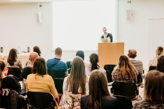 Speaker Giving a Talk at Business Meeting. Audience in the conference hall. Business and Entrepreneurship. Focus on unrecognizable people from rear.