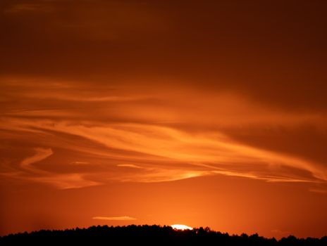 Orange sunset with clouds in flow and dark mountain range