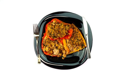 black plate with gratin peppers on a white background