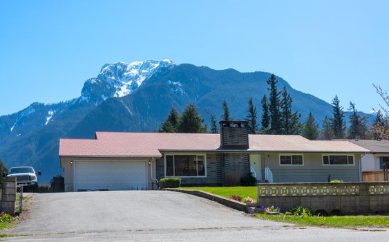 Canadian mountain landscape overview with residential house in front.