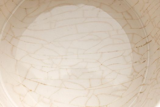 cracked glaze on the bottom of a white ceramic cup full frame closeup background