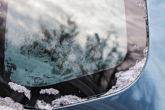 winter hoarfrost pattern on car window glass at daylight close-up with selective focus and shallow depth of field