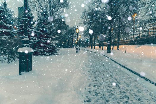 alley with street lamps of the Alexander Garden on a winter night in heavy snowfall. fluffy white snow swirls beautifully