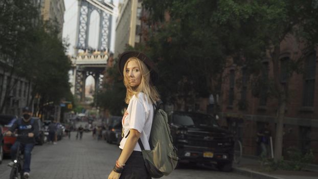 Fashion video of pretty woman near the Brooklyn Bridge in New York City at Sunrise. Young traveling woman in a hat enjoying American holidays.