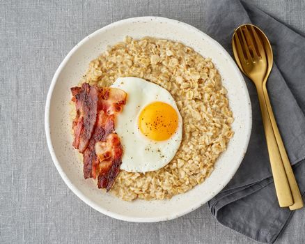 Oatmeal, fried egg and fried bacon. Hearty fat high-calorie breakfast, source of energy. Balance of proteins, fats, carbohydrates. Balanced food, clean eating. Intuitive conscious food. Lactose free