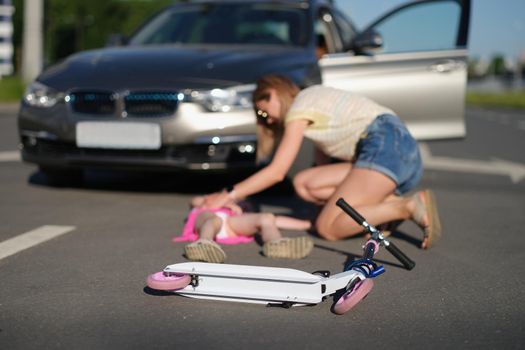 Low angle of girl with scooter hit on road by automobile, mother worry about kid, road accident. Car driver didnt notice child. Accident, violation concept