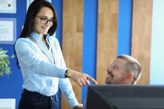 Portrait of woman and man in office discuss something, woman point with finger on screen. Friends share ideas at work. Business, creative, company concept