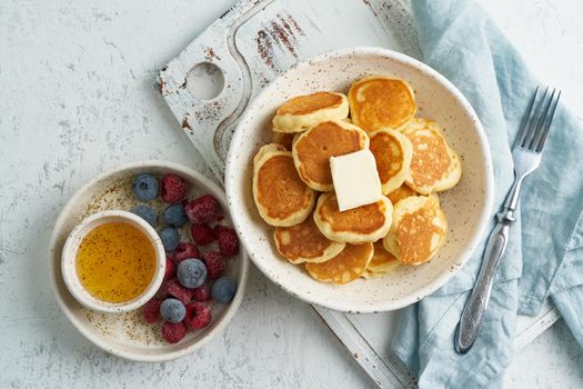 Pancakes cereal, tiny thin funny crumpet, children's food. Breakfast with drink, white table, bright morning, top view