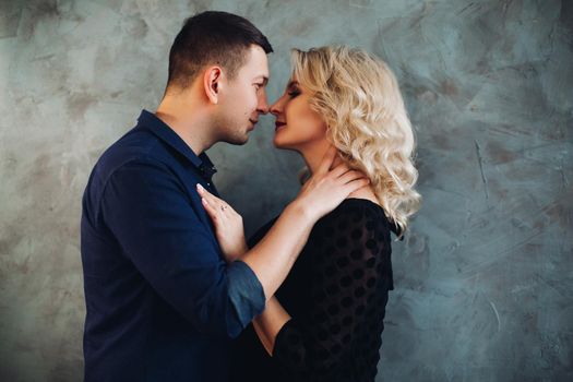 Portrait of sensual couple, man looking in the eye to his charming blonde woman. Boyfriend touches the neck of girlfriend and she holds hand on his chest.Concept of love,relationship and passion.