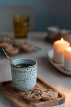 Christmas background with Chocolate chip cookies, cup of tea. Cozy evening, mug of drink, holiday decorations, candles lights bokeh. Vertical still life twilight