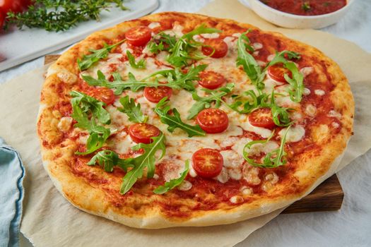 Rustic Italian homemade Pizza Dough margherita topped with pizza sauce from canned tomatoes, mozzarella cheese and arugula, side view