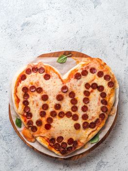 Father's day background with pizza in heart shape and dad word. Pepperoni pizza in heart-shape with dad lettering on gray background.Copy space for text. Father day concept,recipe and idea. Vertical