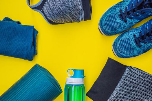 Everything for sports turquoise, blue shades on a yellow background. Yoga mat, sport shoes sportswear and bottle of water. Concept healthy lifestyle, sport and diet. Sport equipment. Copy space.