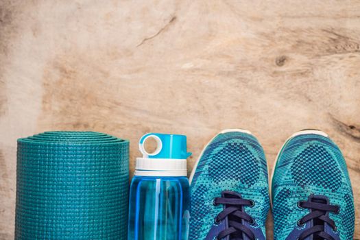 Everything for sports turquoise, blue shades on a wooden background. Yoga mat, sport shoes sportswear and bottle of water. Concept healthy lifestyle, sport and diet. Sport equipment. Copy space.