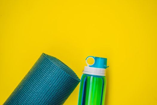Everything for sports turquoise, blue shades on a yellow background. Yoga mat, sport shoes sportswear and bottle of water. Concept healthy lifestyle, sport and diet. Sport equipment. Copy space.