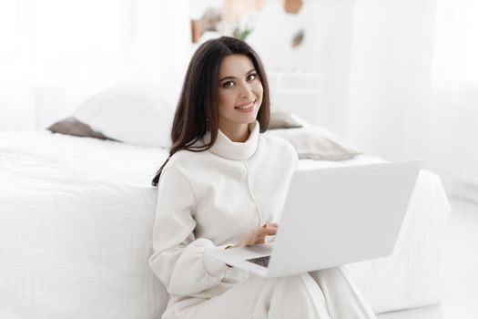 young woman working in laptop at home indoor in white colours. High quality photo