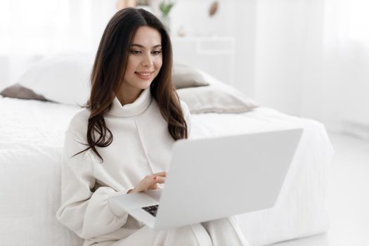 young woman working in laptop at home indoor in white colours. High quality photo