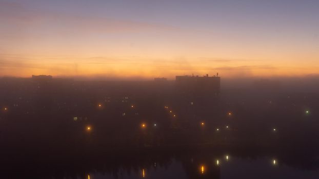 SEVERODVINSK, RUSSIA - MARCH, 11, 2021: Bright winter sunset against the background of houses. Multi-story houses in the rays of the sun. The sun goes down behind the houses