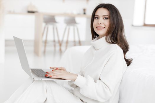 young woman working in laptop at home indoor in white colours. High quality photo