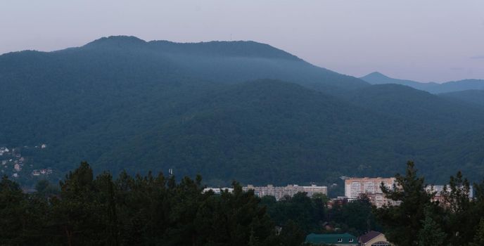 LAZAREVSKOE, SOCHI, RUSSIA - MAY, 27, 2021: Panorama of sunset in the mountains. A magical view of the sea and small town from the observation deck.