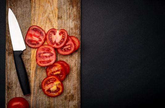 Sliced cherry tomatoes with knife on wooden board on background with copyspace. Healthy organic pomodoro vegetable for bruschetta view from above
